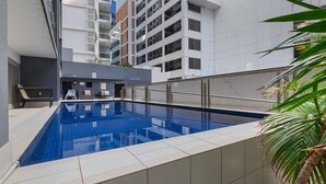 Una piscina interior moderna con plataforma azulejada, rodeada de edificios altos.