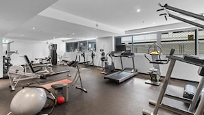 Un gimnasio con varios equipos de ejercicio, incluyendo cintas de correr, máquinas de pesas y una bicicleta estática.