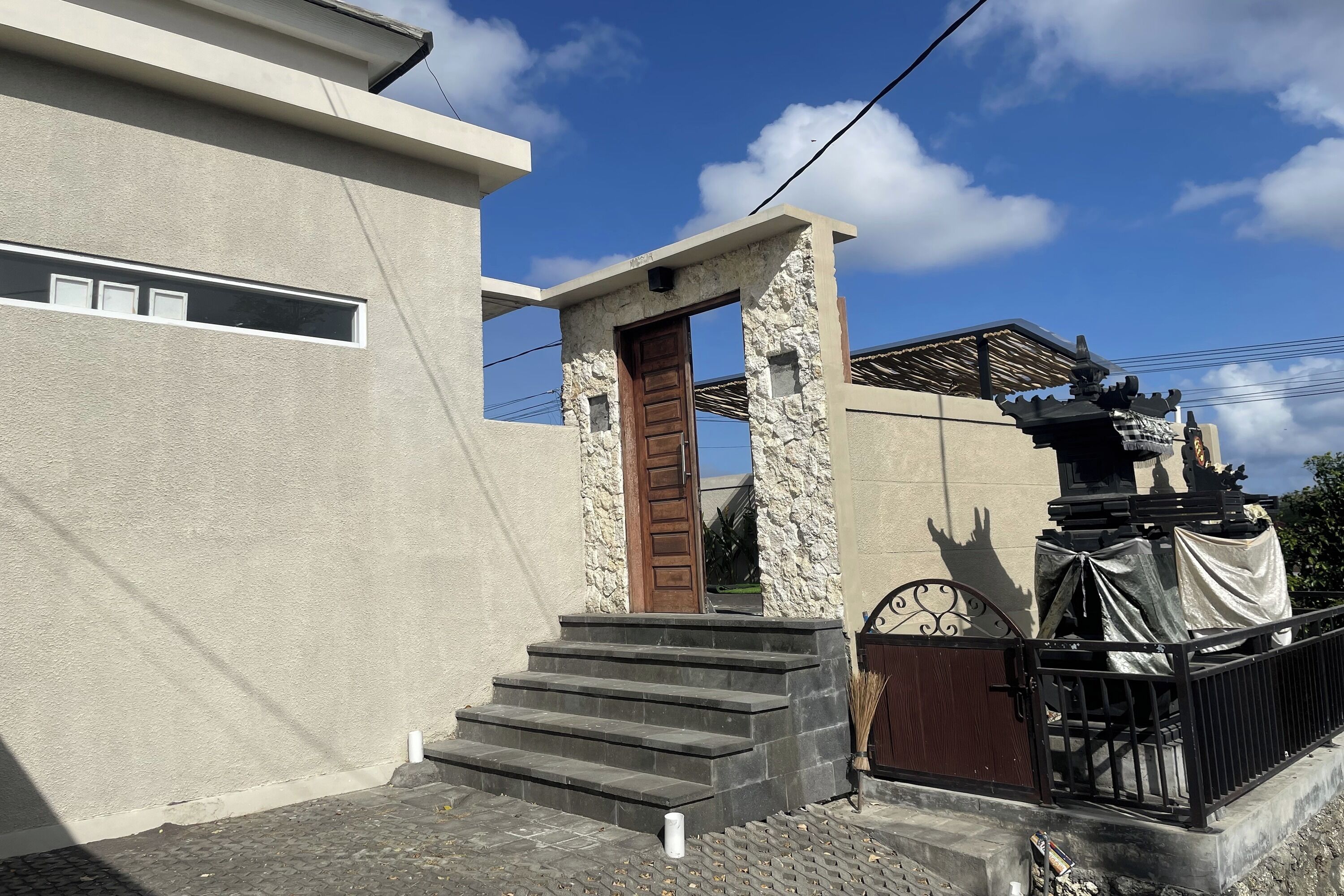 Un bâtiment moderne avec une entrée en pierre, une porte en bois et un portail en métal.