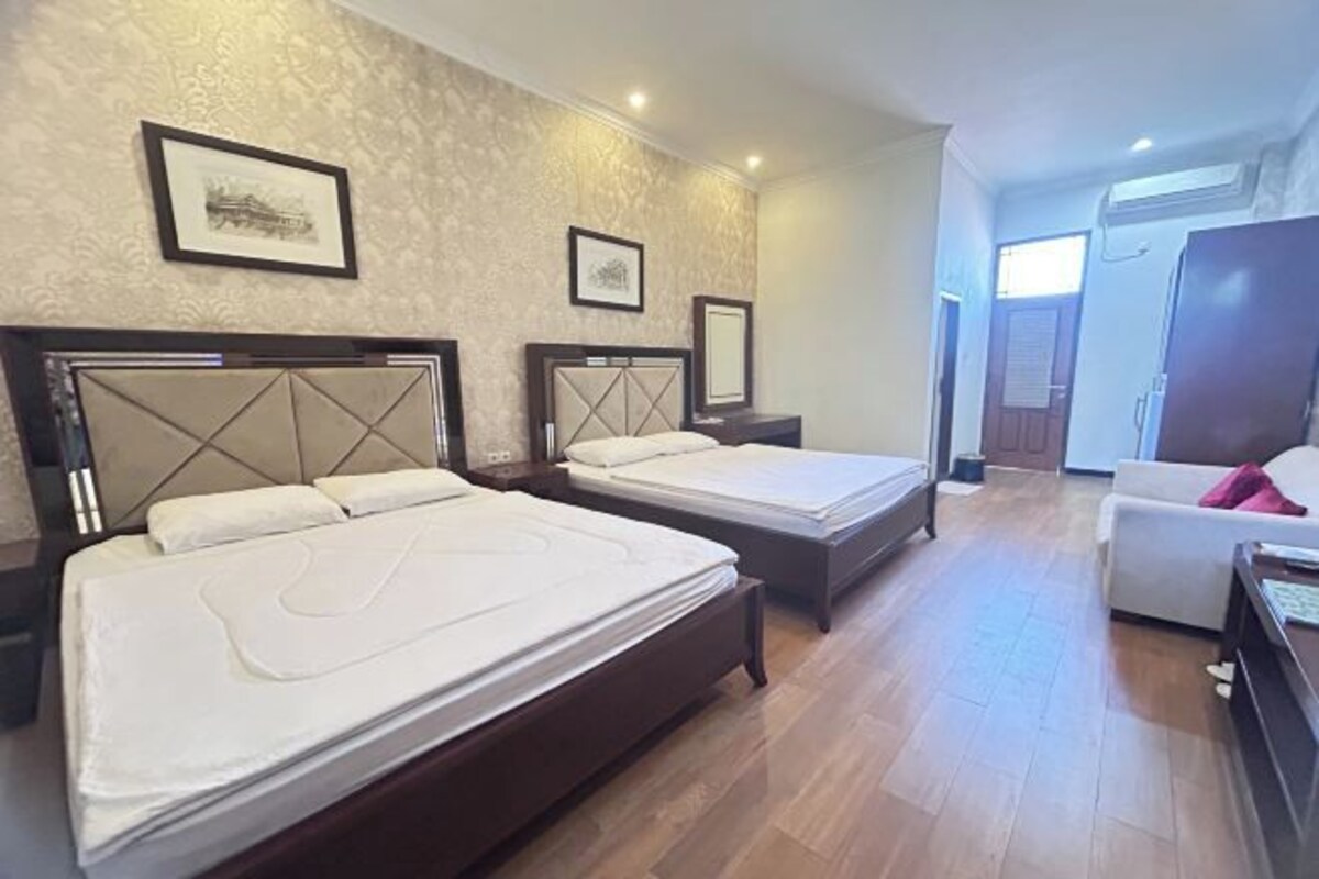 A hotel room with two beds, a sofa, and a wardrobe.