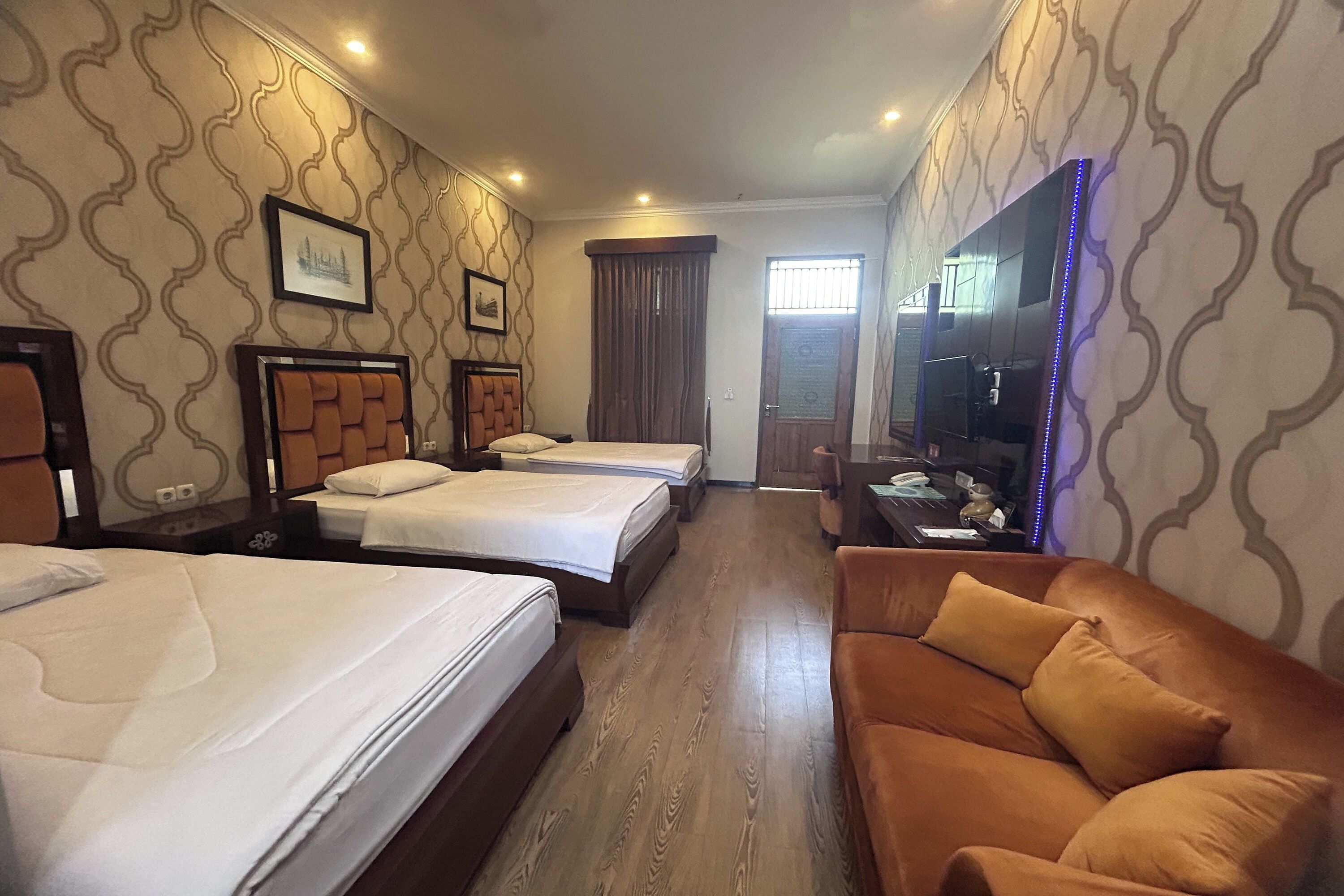Habitación de hotel con dos camas, un sofá, un televisor y una ventana con cortinas.