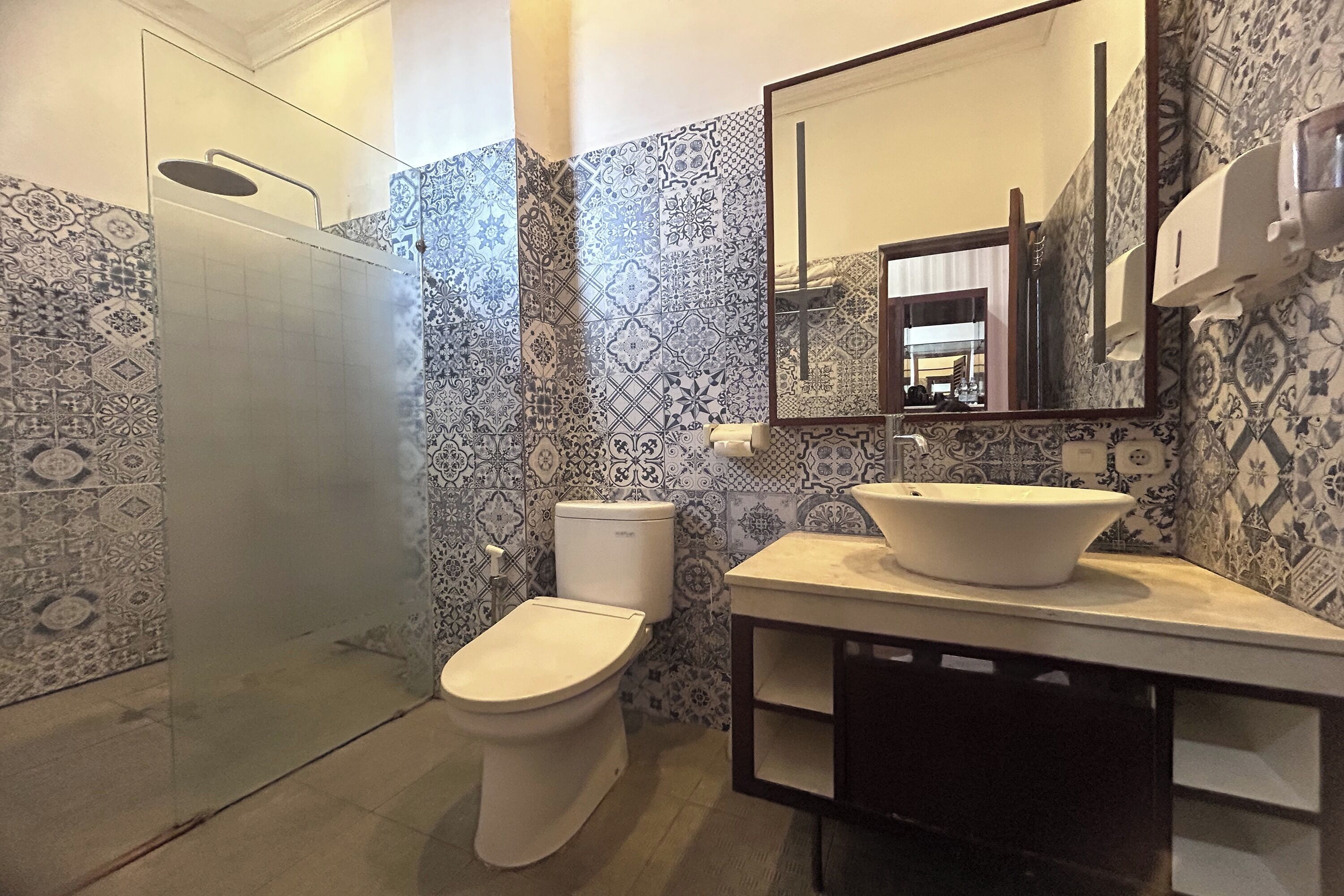 A bathroom with patterned tiles, a toilet, a sink with a basin, and a mirror.