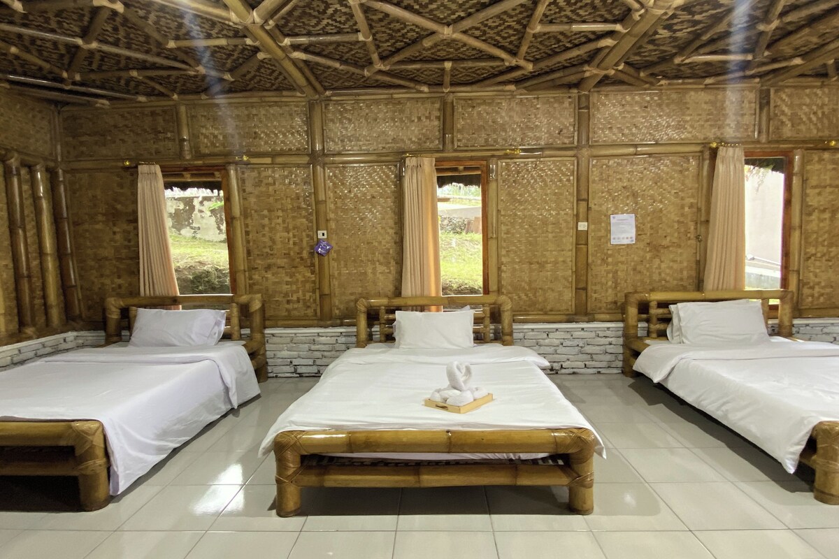 A room with three wooden beds, white bedding, and a bamboo ceiling.