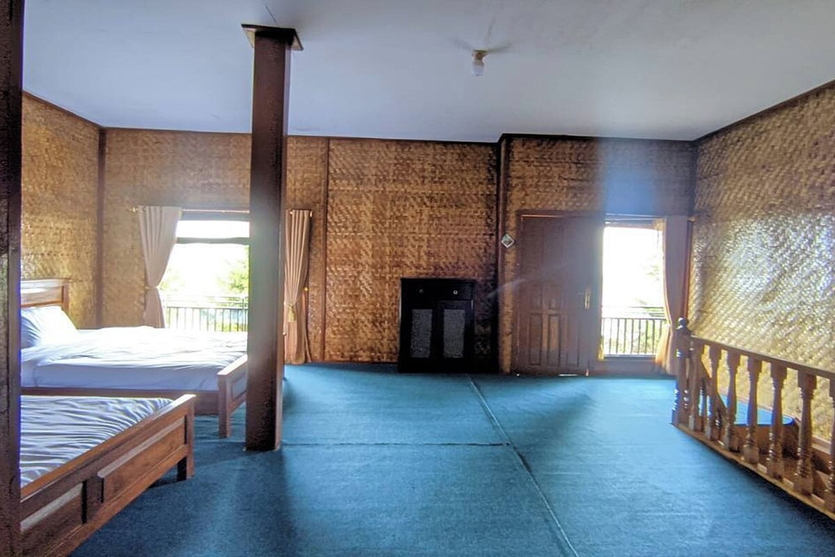 A room with a bed, a wooden pillar, a wardrobe, and a view of the outdoors.