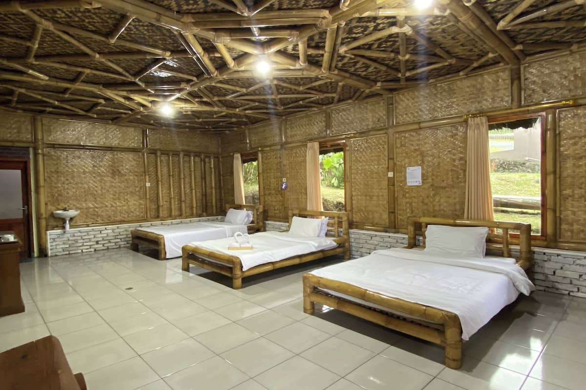 Quarto com três camas de madeira, piso de azulejos brancos e teto de bambu.