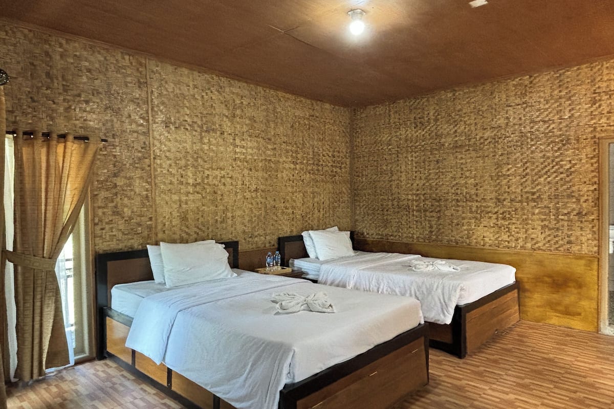 Quarto com duas camas, cabeceiras de madeira e parede com padrão de tijolos.