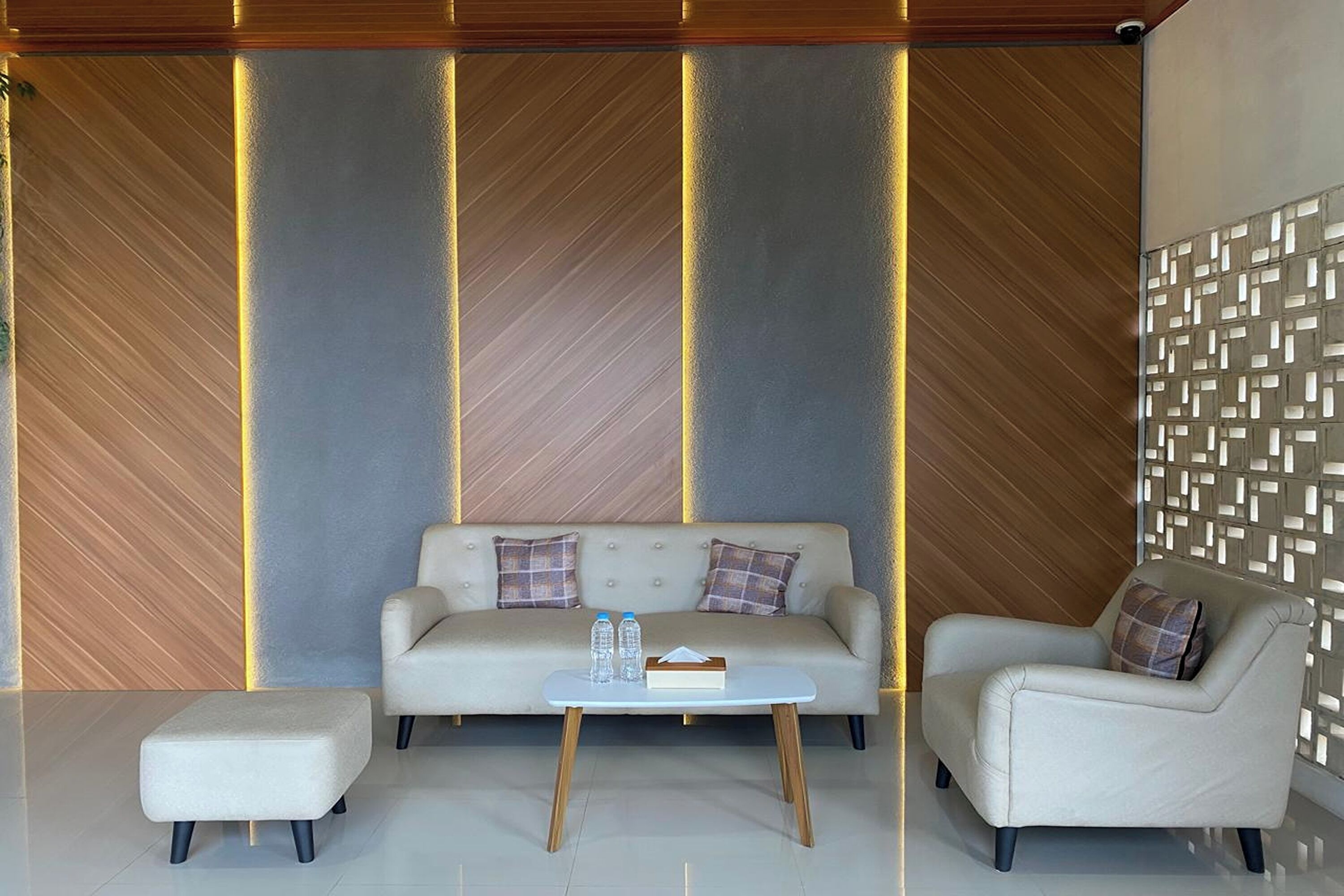 Una sala de estar moderna con un sofá, dos sillones, una mesa de centro y una pared con diseño.