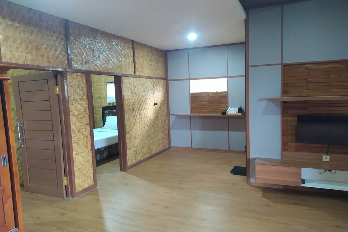 A room with a wooden floor, a TV on a wooden stand, and a sliding door.