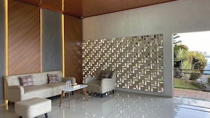A modern lobby with a sofa, armchairs, a coffee table, and a decorative wall. - Puncak Darajat Highland (Cibuniherang)
