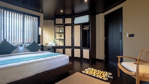 Une chambre d’hôtel moderne avec un grand lit, une chaise en bois, un bureau et une armoire.