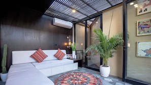 Un salon moderne avec un canapé blanc, un tapis à motifs et une grande plante en pot.