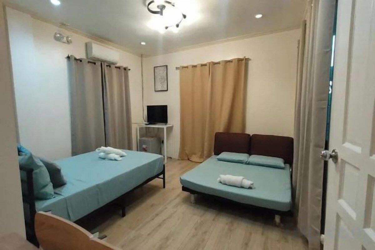 A room with two single beds, a desk with a computer, and a television.