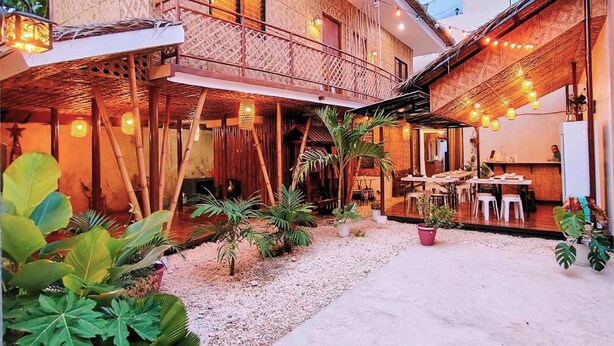 A two-story building with a balcony, outdoor seating area, and string lights. - Intoy's Place Panglao near Beach (Panglao)