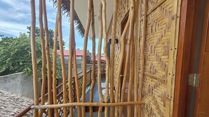 A bamboo-framed balcony with a woven wall and a view of buildings in the background. - Intoy's Place Panglao near Beach (Panglao)
