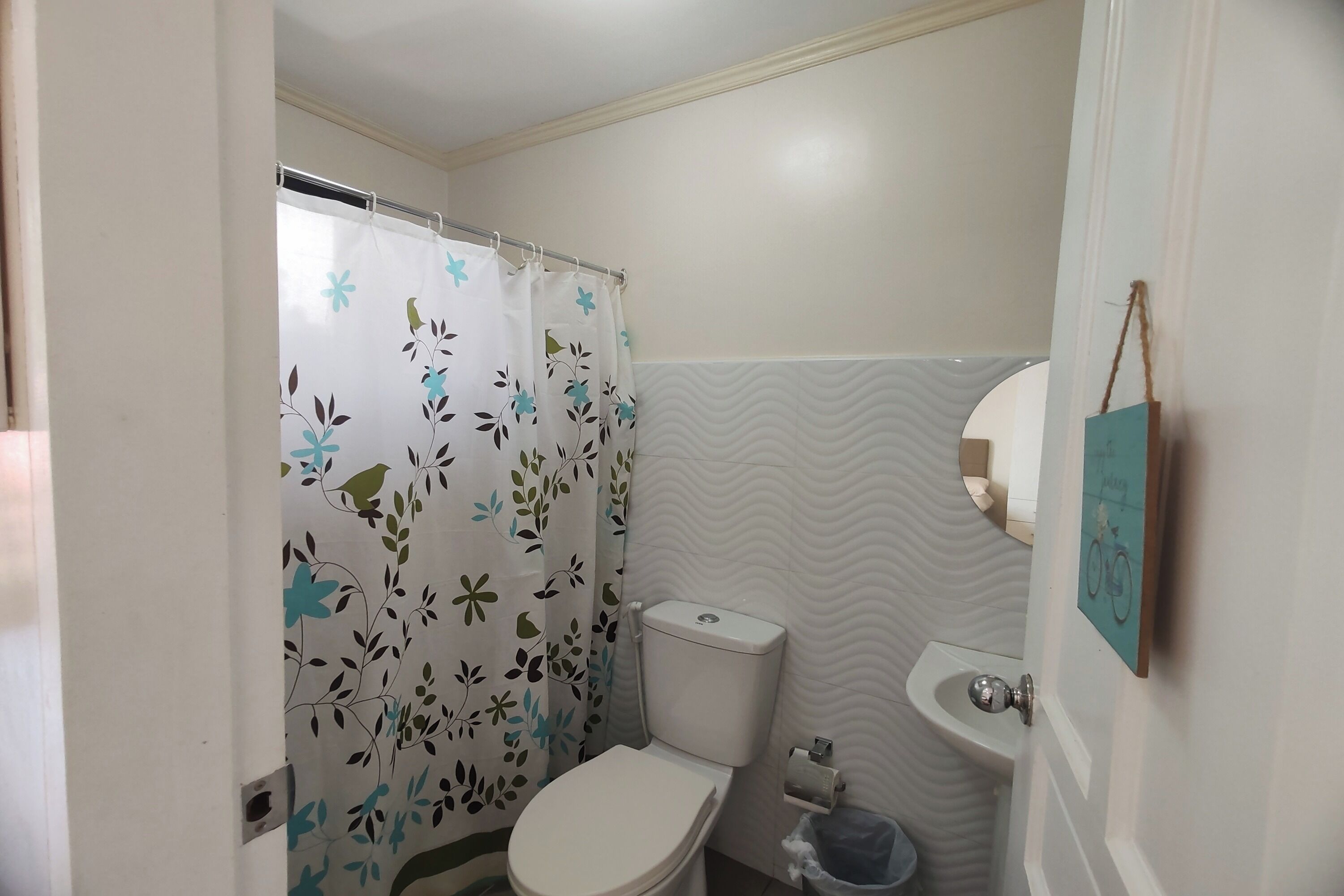 Un baño con inodoro, lavamanos y cortina de ducha con estampado floral.