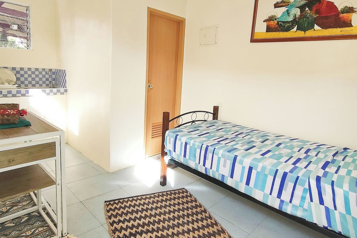 A bedroom with a bed, a desk, and a chair.