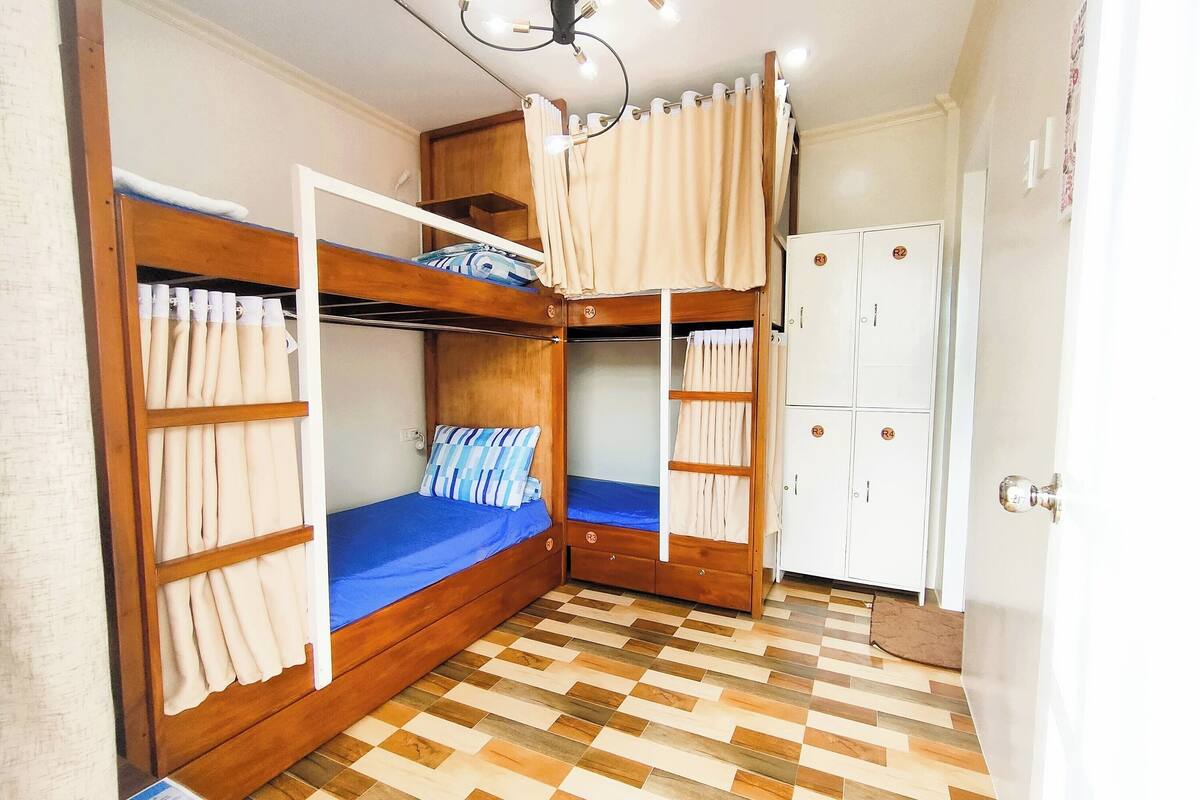 A room with two bunk beds, a white wardrobe, and a patterned floor.