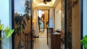 A hotel lobby with a reception desk, seating area, and a view of the interior through a glass door. - Intoy's Place Panglao near Beach (Panglao)