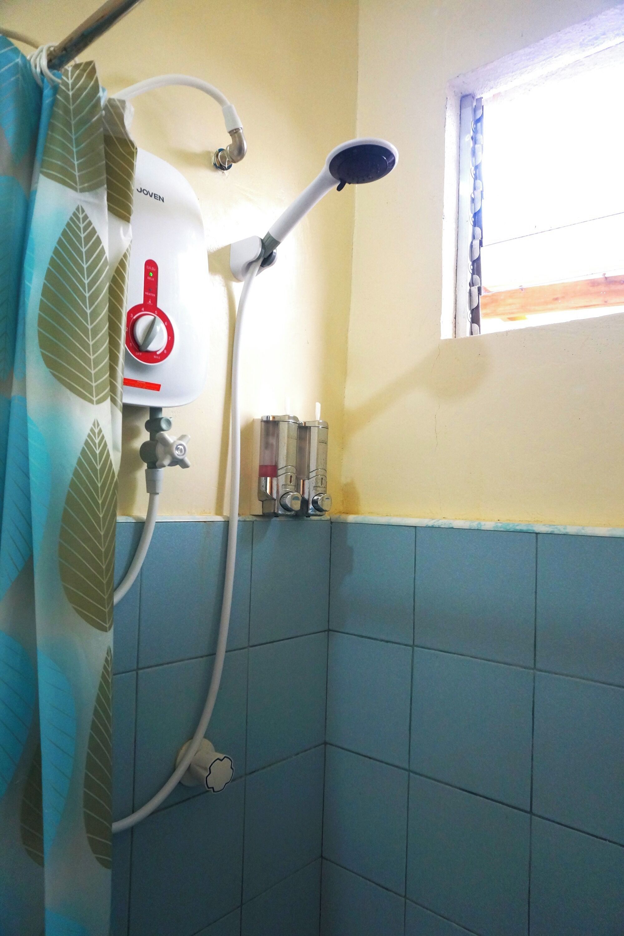 A bathroom with a shower, a window, and a towel rack.