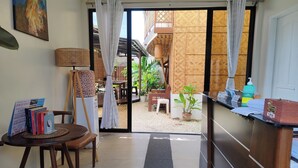 A room with a desk, a chair, a bookshelf, a window with curtains, and a view of the outside. - Intoy's Place Panglao near Beach (Panglao)