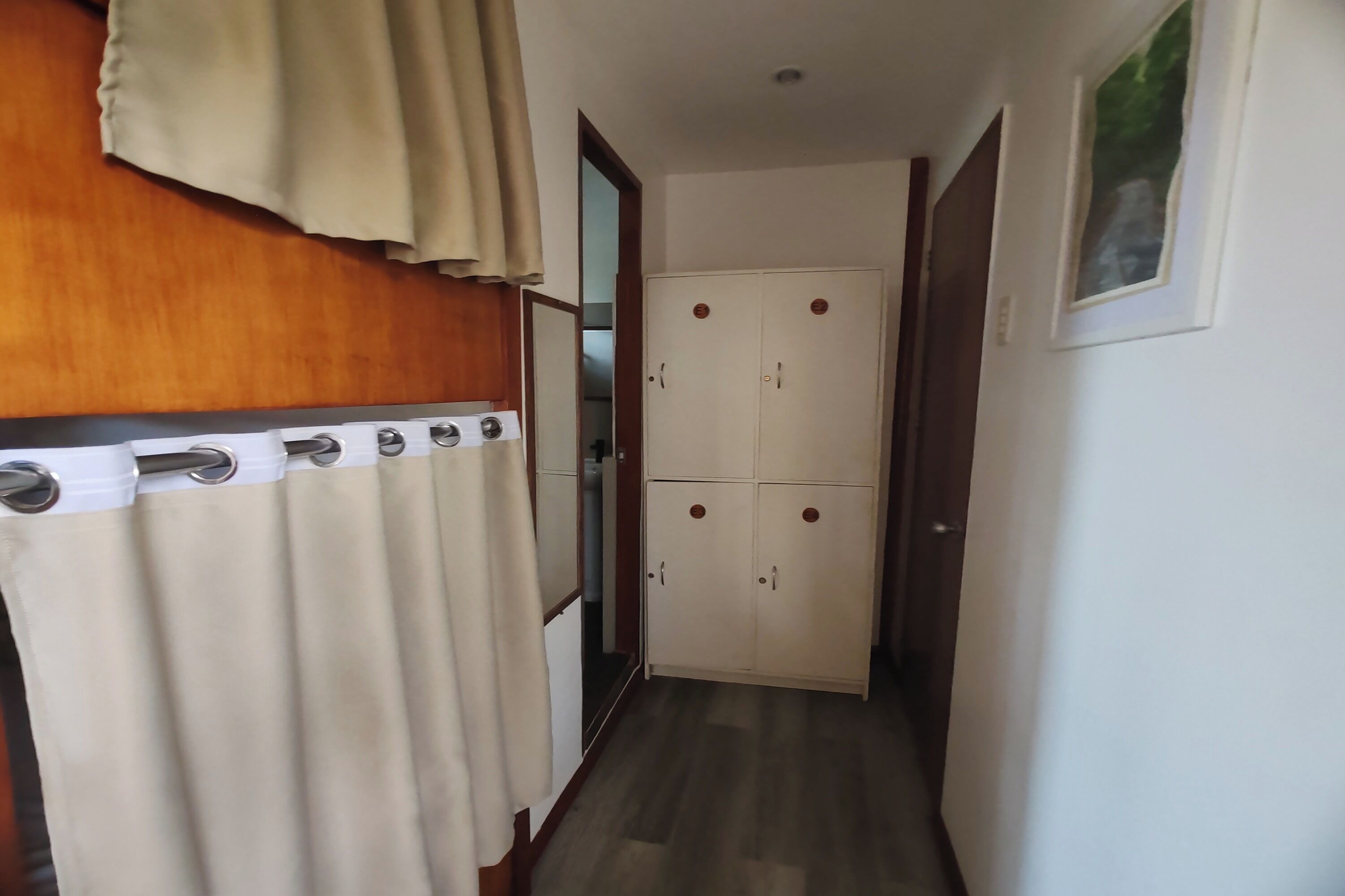 A narrow hallway with a wooden door and a white wardrobe with two doors.