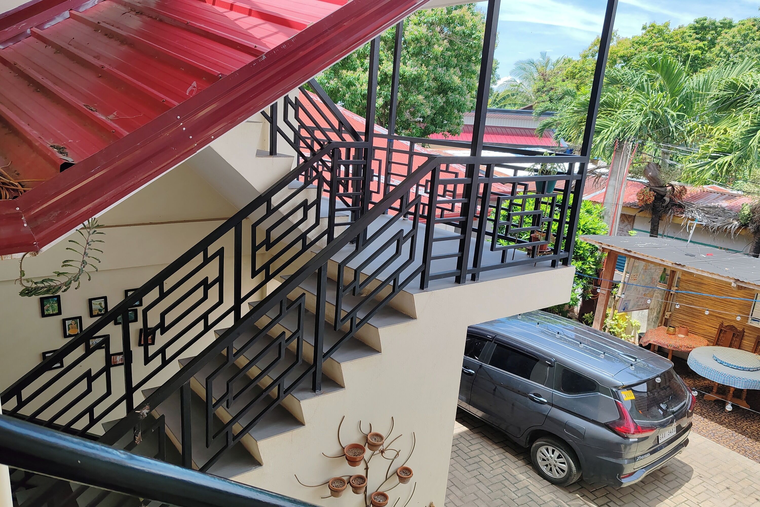 A multi-level building with a staircase, a parked car, and outdoor furniture.