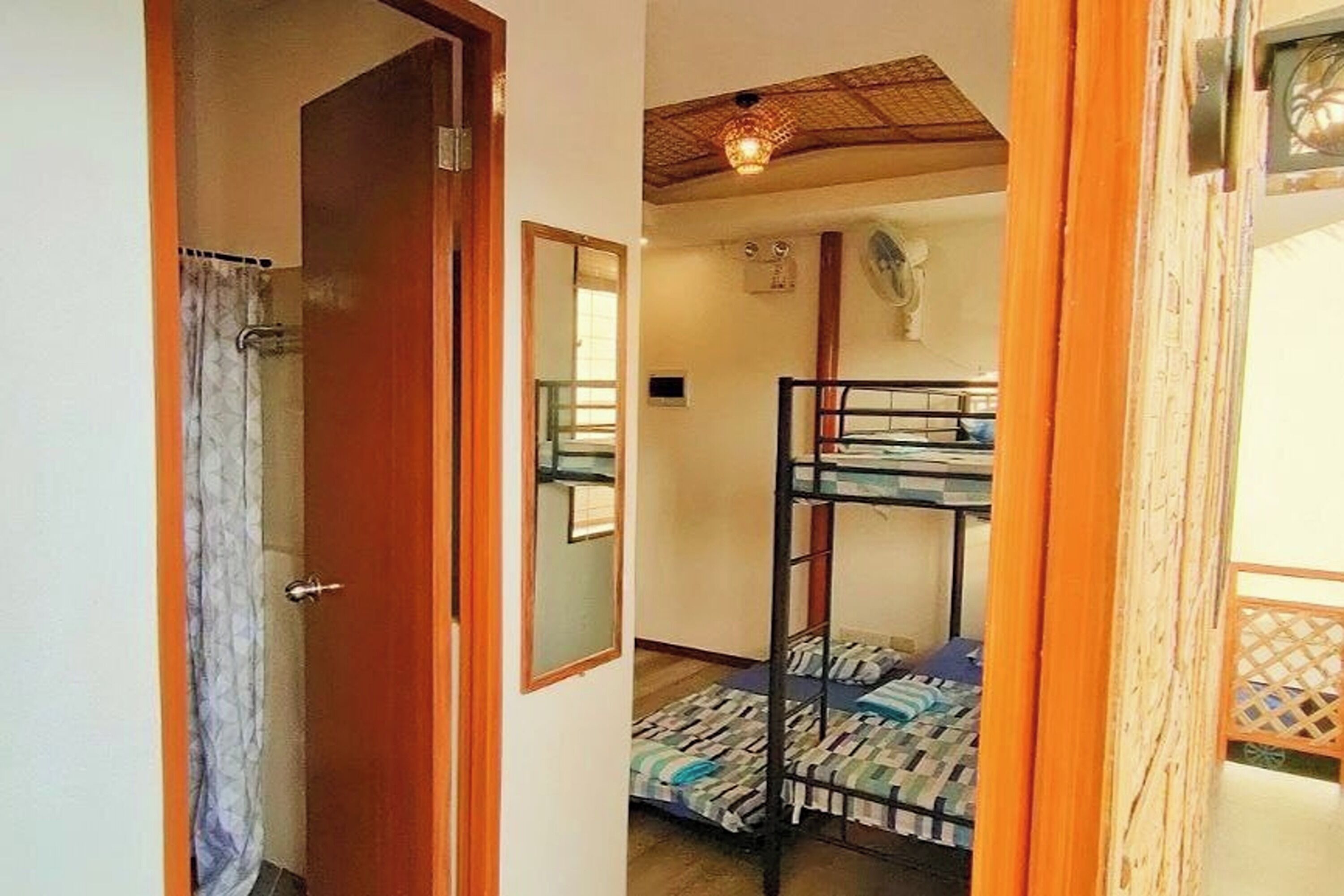 A bunk bed room with a wooden door, a mirror, and a ceiling fan.