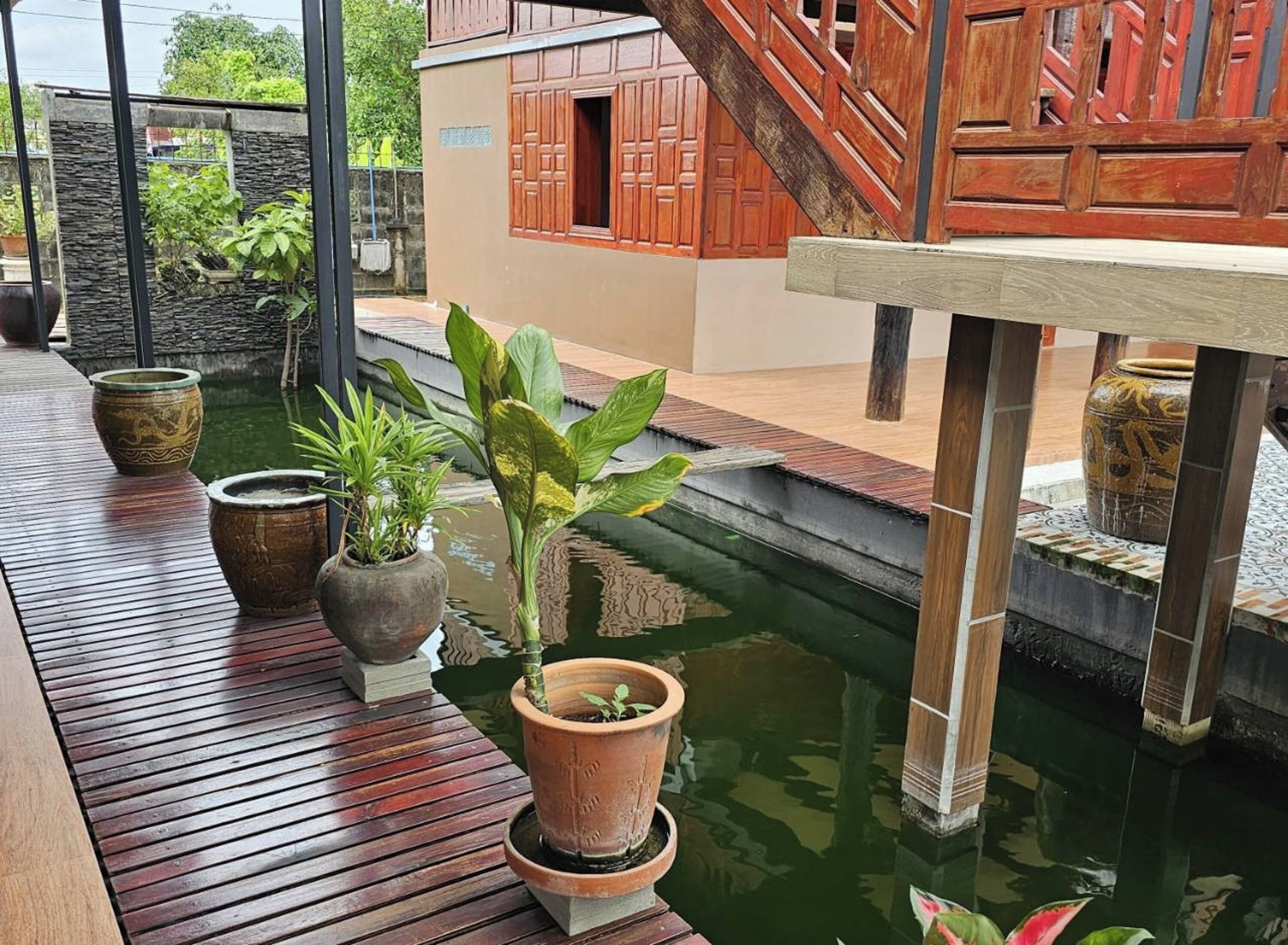 A wooden deck with potted plants and a small water feature.