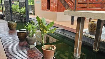 A wooden deck with potted plants and a small water feature.
