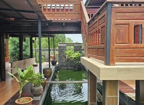 A covered outdoor area with a water feature, wooden structures, and potted plants. - Nipatra Homestay (Bangkok)