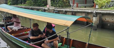 Un bote estrecho con toldo, pasajeros y amarrado.
