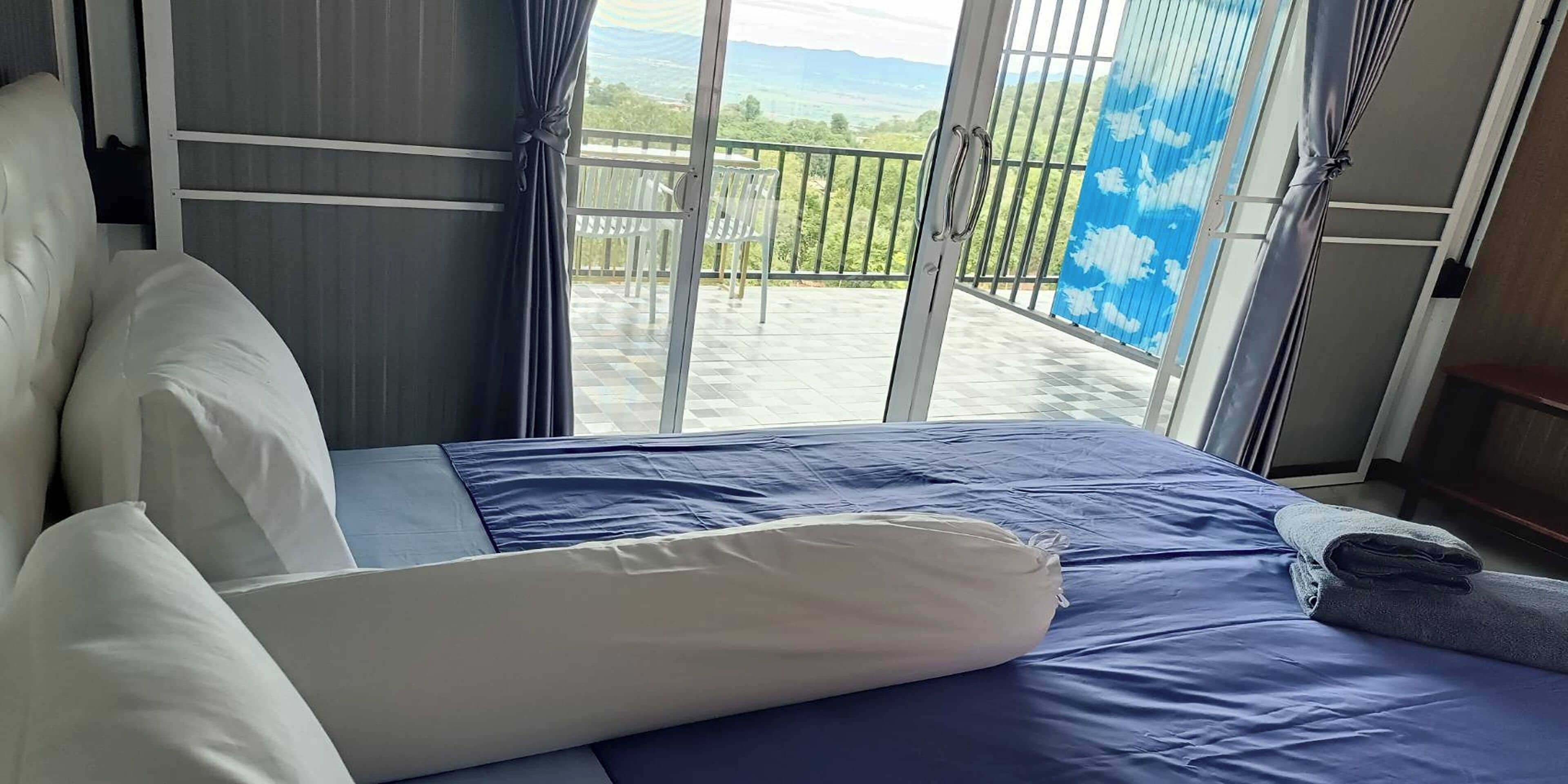 Et hotelværelse med en seng, udsigt til en balkon med gelænder, og et vindue med gardiner.