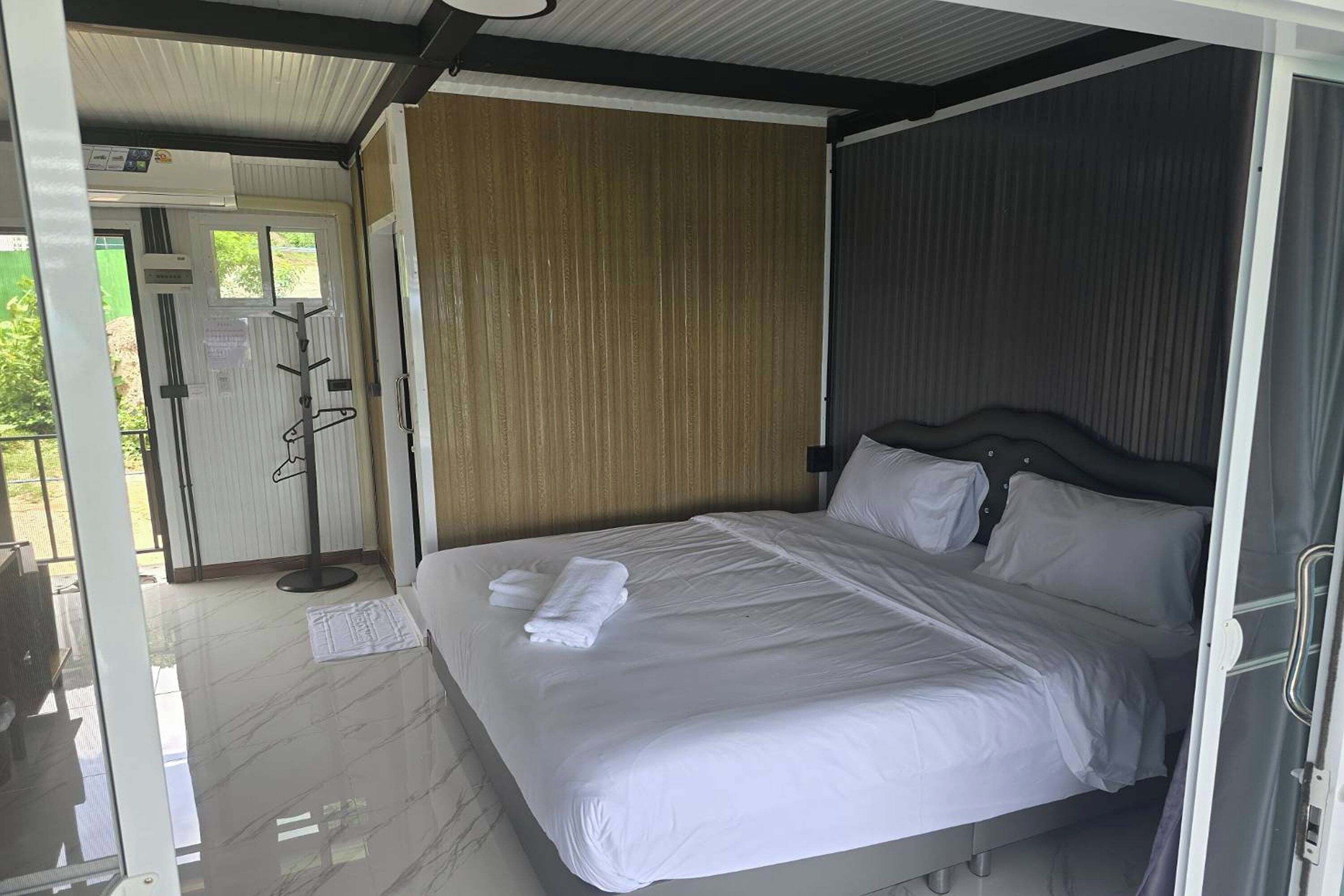 A hotel room with a bed, a wooden panel wall, and a door leading to a balcony.