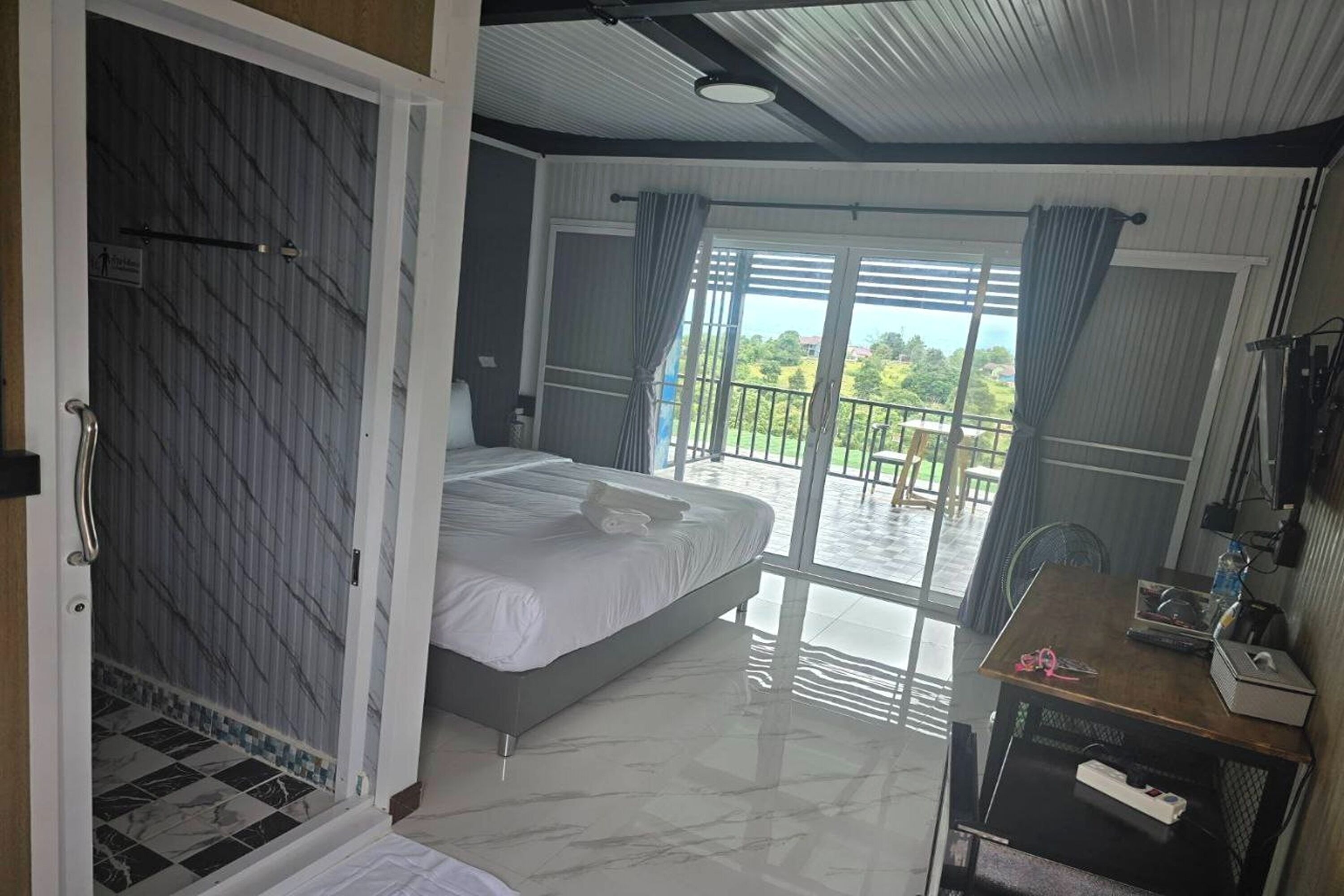 Une chambre à coucher avec un lit, un bureau et une vue sur l’extérieur.