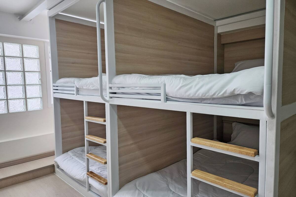 A bunk bed room with a wooden headboard, a window with frosted glass, and a white door.
