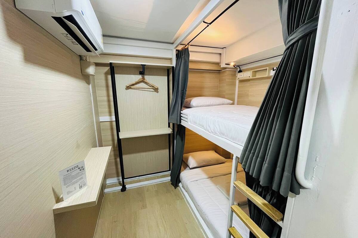 A compact room with bunk beds, a small shelf, and an air conditioning unit.