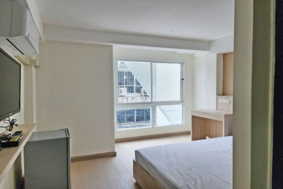 A bedroom with a bed, a TV, and a small desk with a computer.