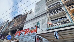 A multi-story building with various signs, including a 24-hour service sign and a Dr. Tiger sign. - Reezq Hostel (Bangkok)