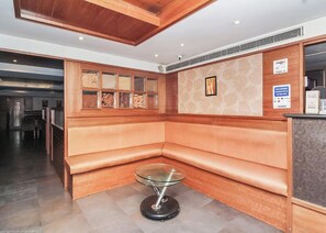 A reception area with a wooden bench, a glass table, and a wall with framed artwork and signs. - Sri Surabhi Luxurious Rooms (Hyderabad)