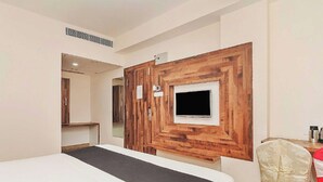 Une chambre d’hôtel comprenant un lit, un mur décoratif en bois avec un téléviseur, un miroir et un bureau avec une chaise.
