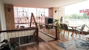 A spacious room with a wooden staircase, a balcony with a view, and a dining area with chairs and a table. - Vilasini Inn (Madduru)