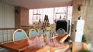 A wooden dining table with chairs, a ladder, and a refrigerator in a room with a view. - Vilasini Inn (Madduru)