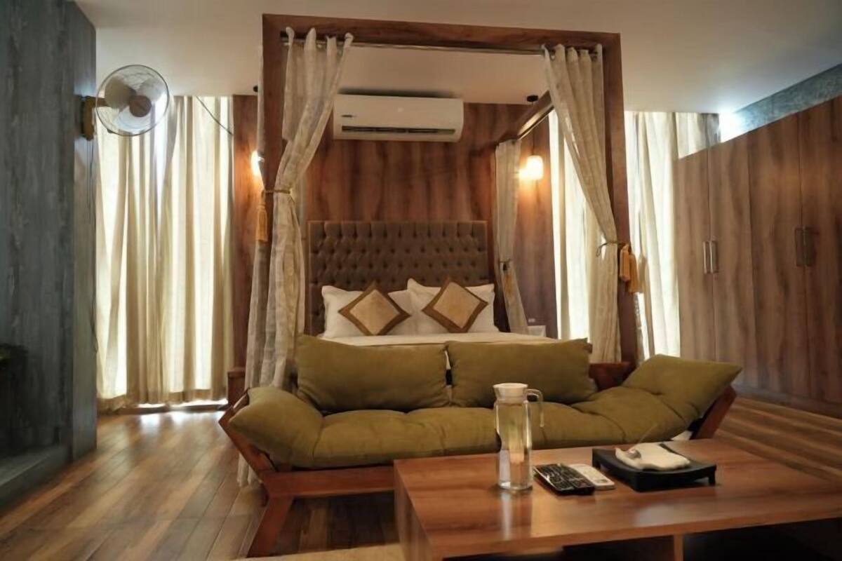 A room with a bed, a sofa, a table, and a fan.