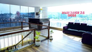 A spacious living area with a balcony, a purple sofa, and a wooden staircase.