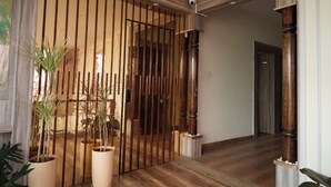 A hallway with a wooden door, potted plants, and a wooden floor. - Vilasini Inn (Madduru)
