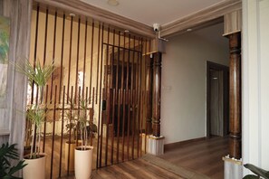 Un couloir avec une porte en bois, des plantes en pot et un plancher en bois.