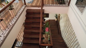 A wooden staircase with a railing, potted plants, and a patterned wall. - Vilasini Inn (Madduru)