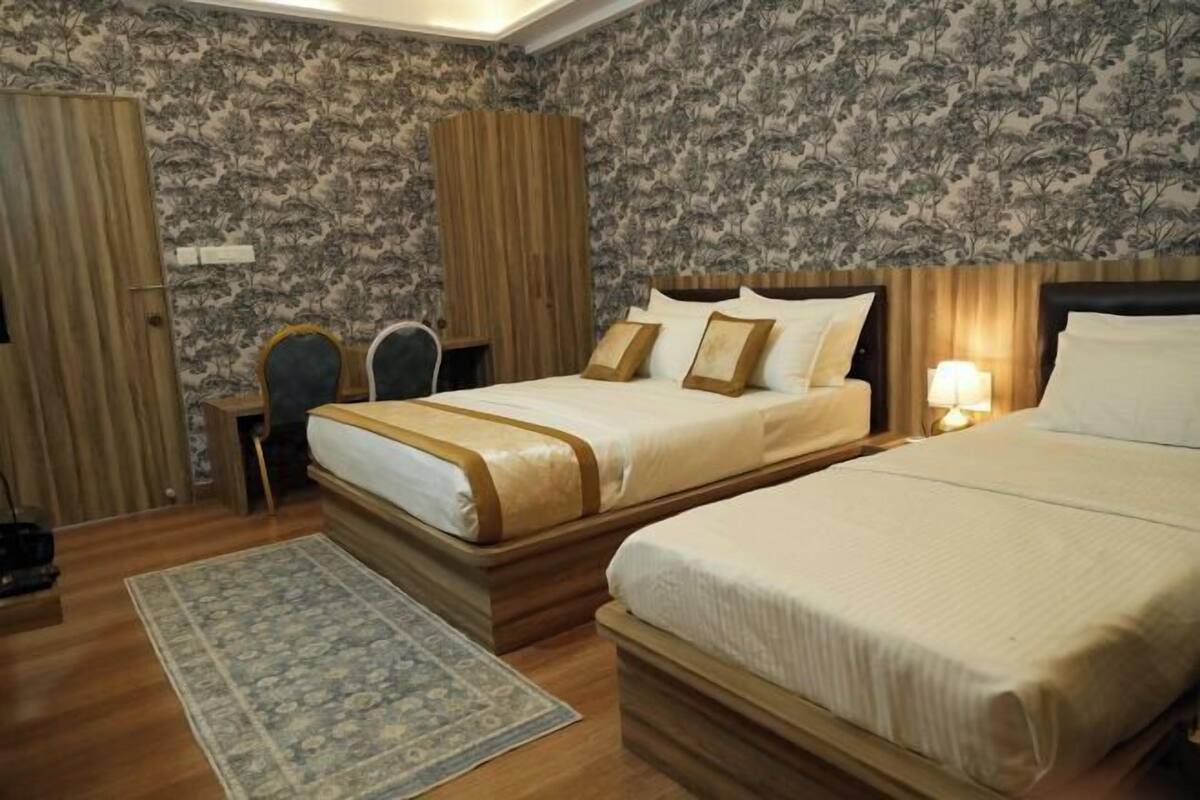 A hotel room with two beds, a desk, a chair, and a wardrobe.