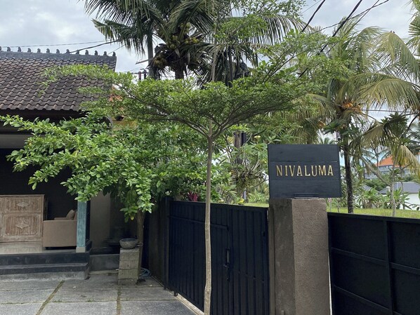 Une entrée fermée par un portail, sur laquelle on peut lire l’inscription « Nivaluma ».