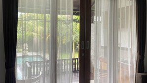 A room with a view of a pool and greenery, featuring sheer curtains and a wooden door. - Nivaluma By Zuzu (Mas)